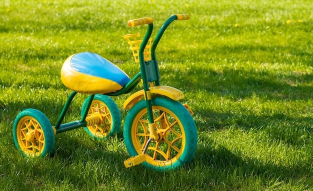 small yellow green children s tricycle standing grass sunny day copy space dailykidfinds